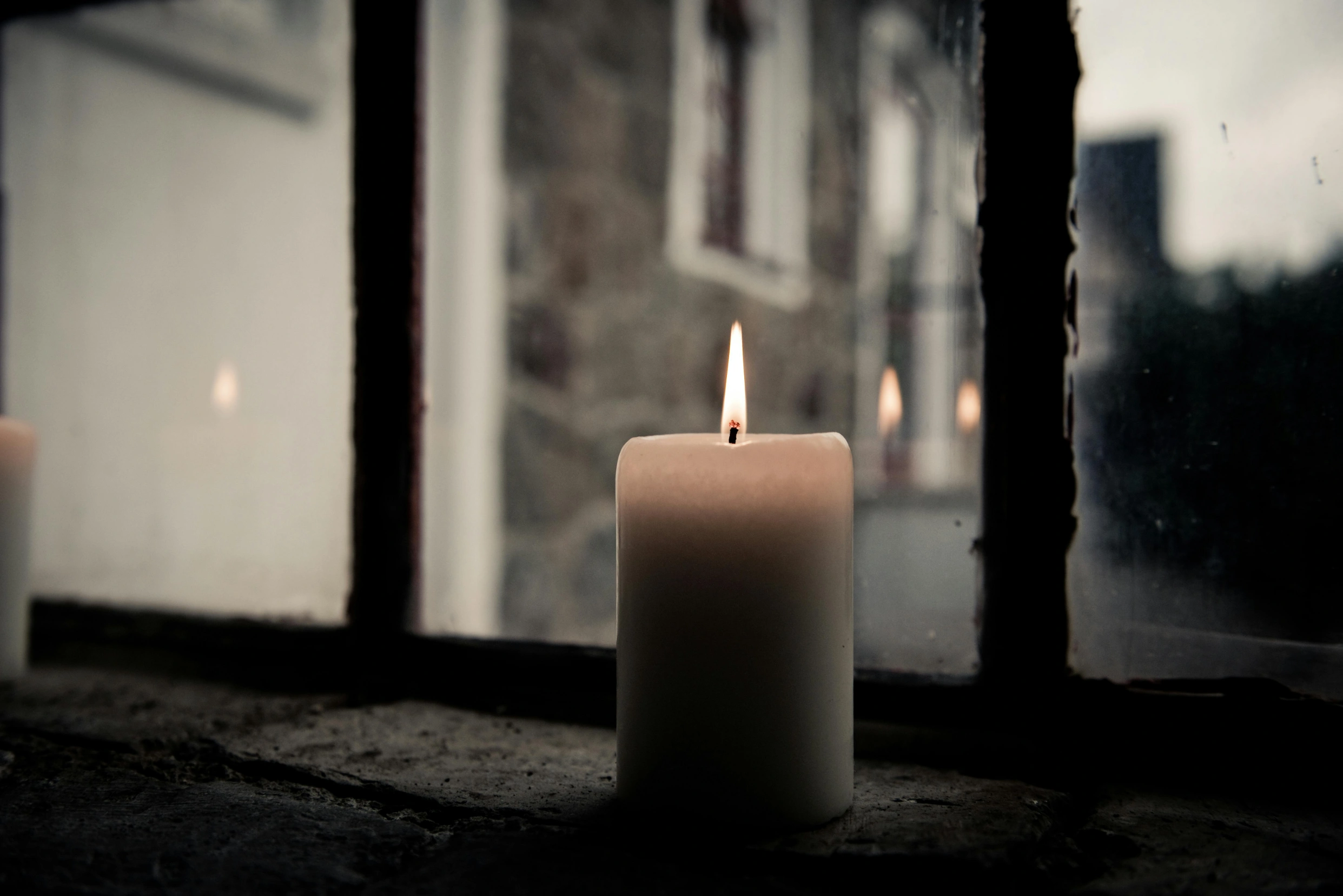 Pillar candle sitting next to window showing street