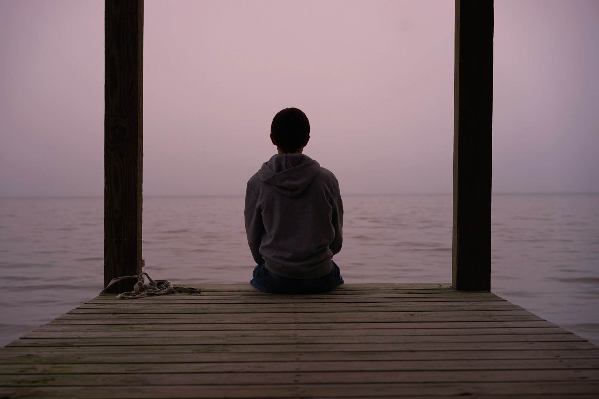 Woman sitting on a dock looking at a lake at sunrise