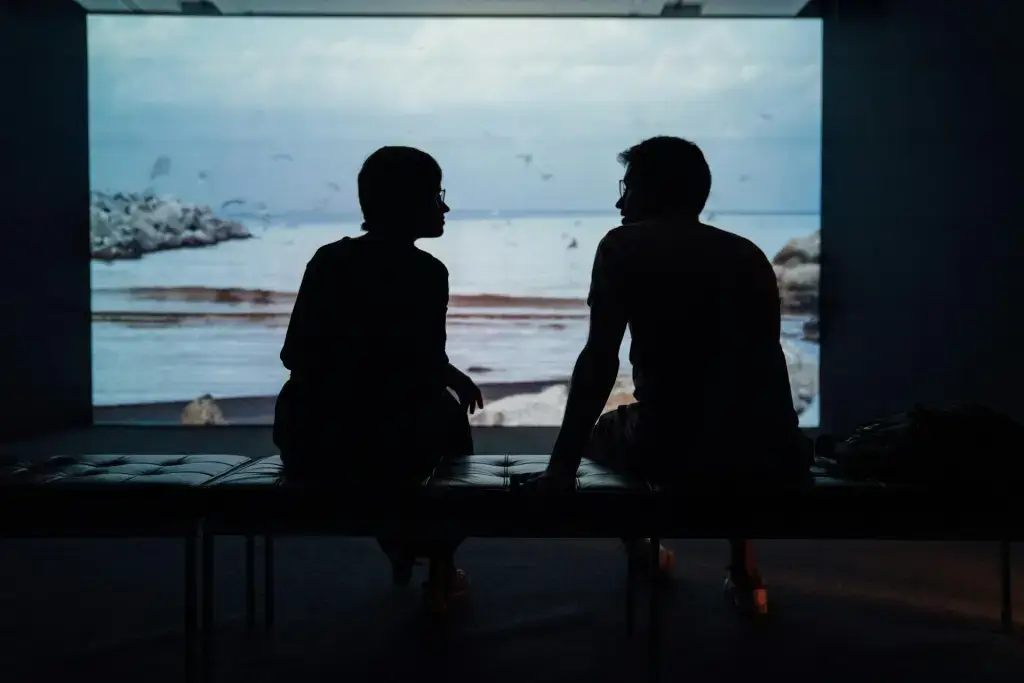 Two people talking looking out at water