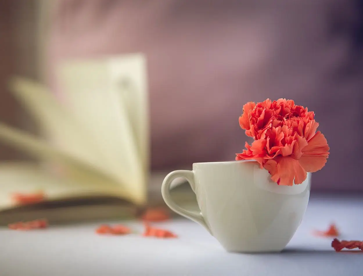 Journal and Coffee mug with carnation on table