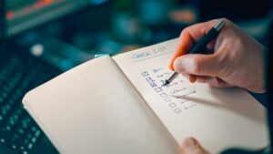 Person writing a checklist in a notebook
