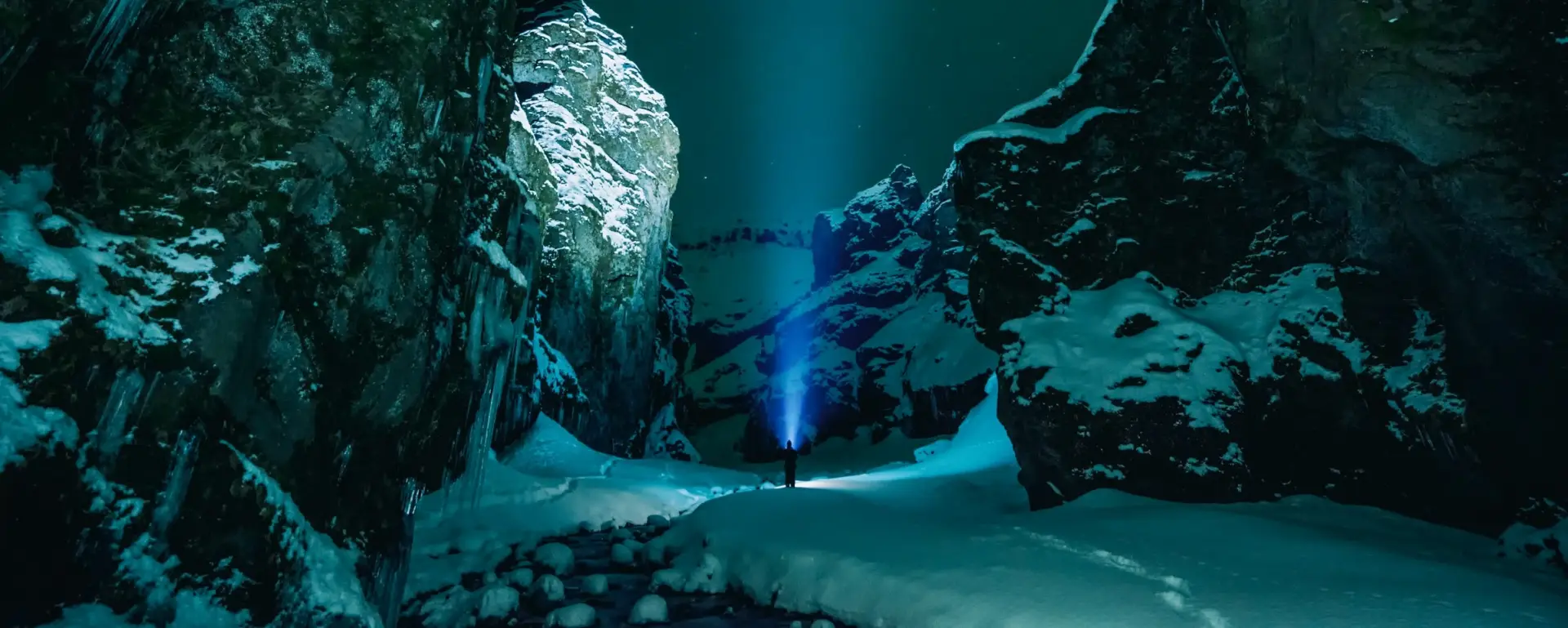 Person in snow covered ravine with light shining on them